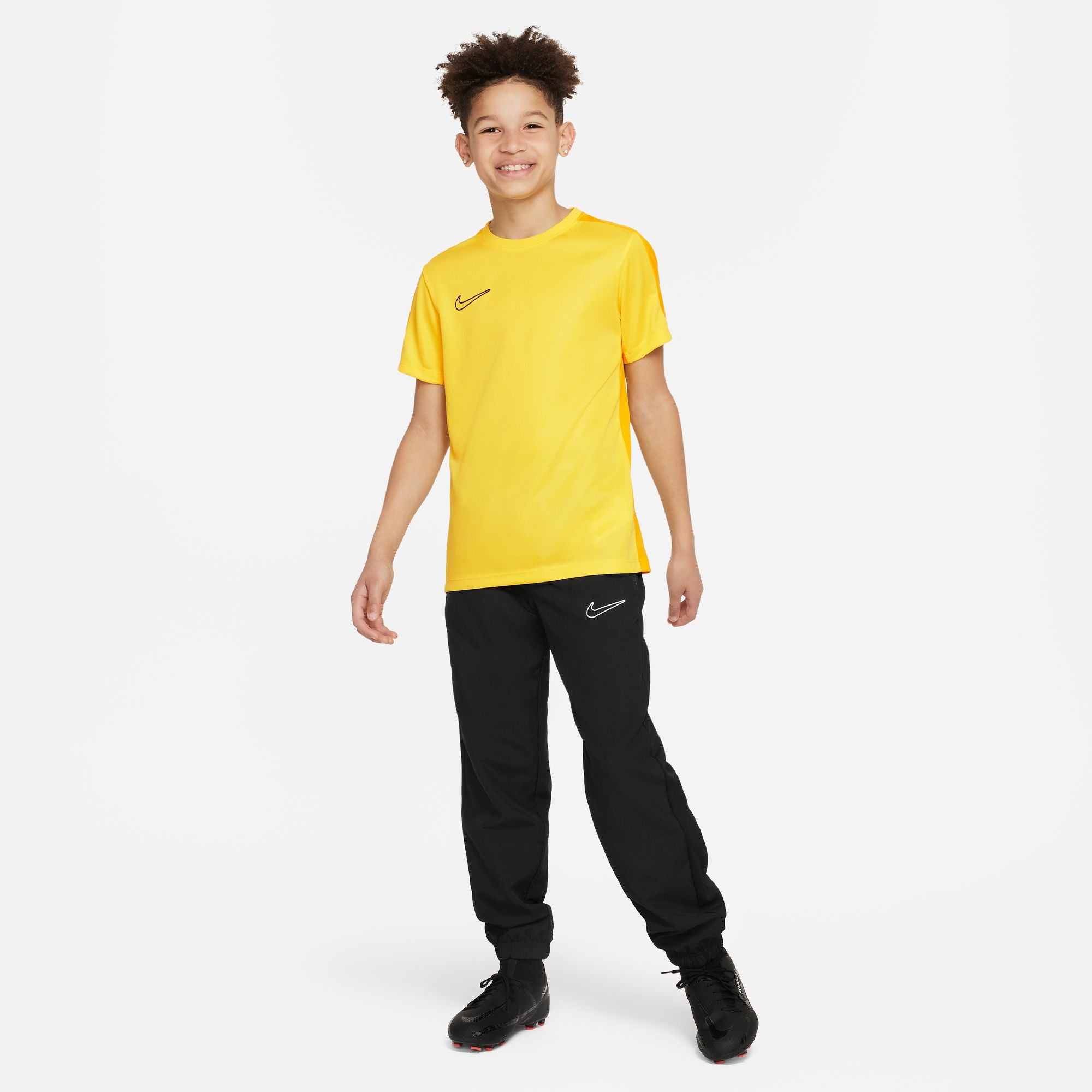 Nike Dri FIT Academy 23 Short Sleeve Tour Yellow Shirt with nike university gold with black nike tracksuit bottoms and black trainers