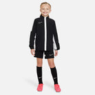 Nike Dri FIT Academy 23 Woven Track Jacket in Black/White with black nike shorts and black nike socks and pink nike football boots