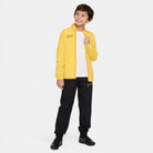 Nike Dri FIT Academy 23 Woven Track Jacket in Tour Yellow/University Gold with black nike tracksuit bottoms and black nike trainers