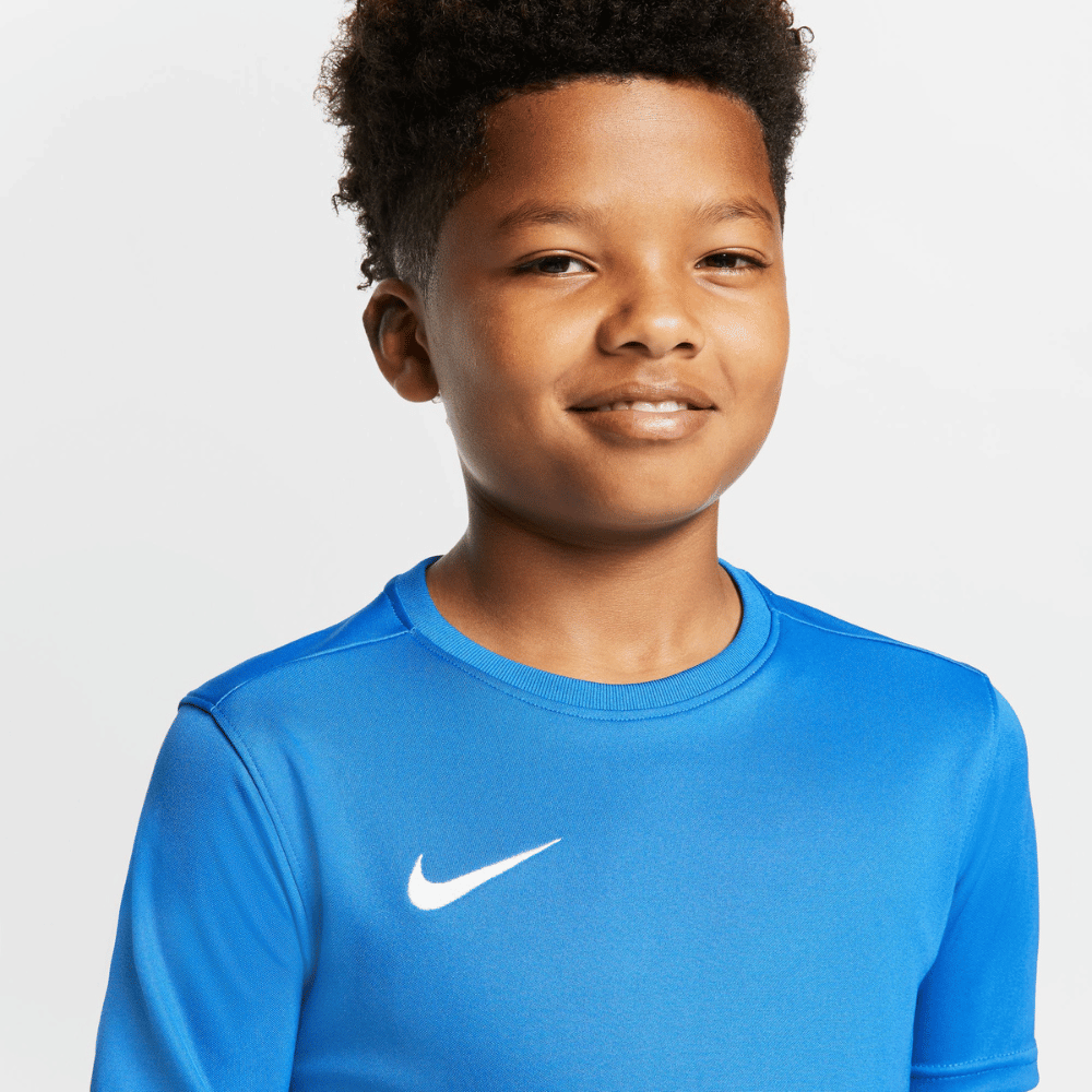 Close up of Boy Wearing Nike Dri FIT Park VII Short Sleeve Shirt in Royal Blue. White swoosh showing.