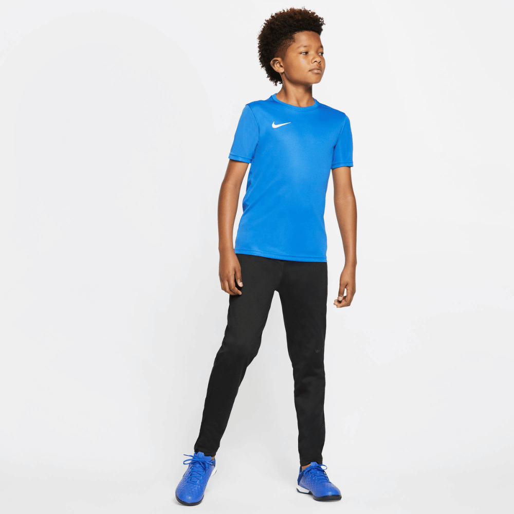 Boy Wearing Nike Dri FIT Park VII Short Sleeve Royal Blue Shirt, black Nike joggers and blue boots